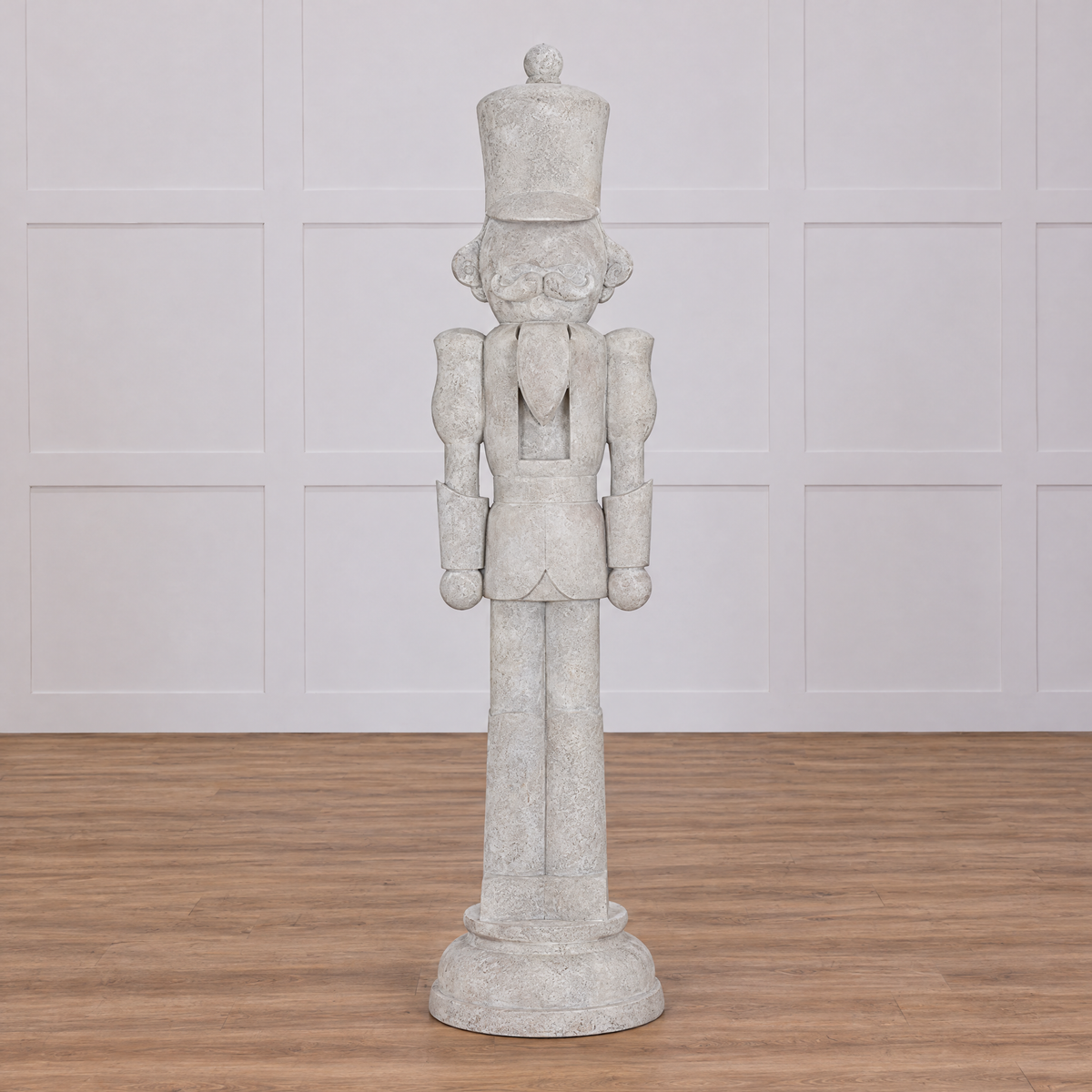 A decorative 8 foot tall nutcracker made from resin, designed to look like an antique stone statue, flanked by holiday decorations and displaying a weathered finish.
